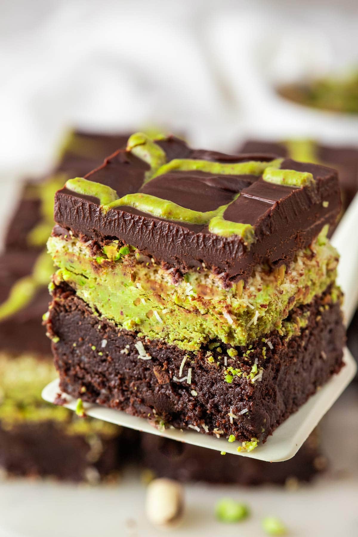 chocolate pistachio brownie lifted up on a spatula.