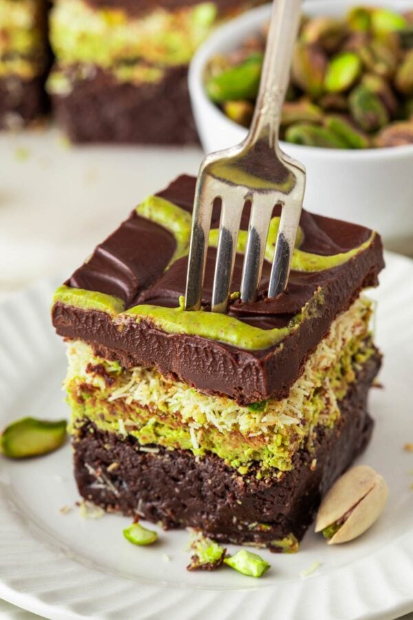 fork digging into a thick chocolate pistachio brownie.