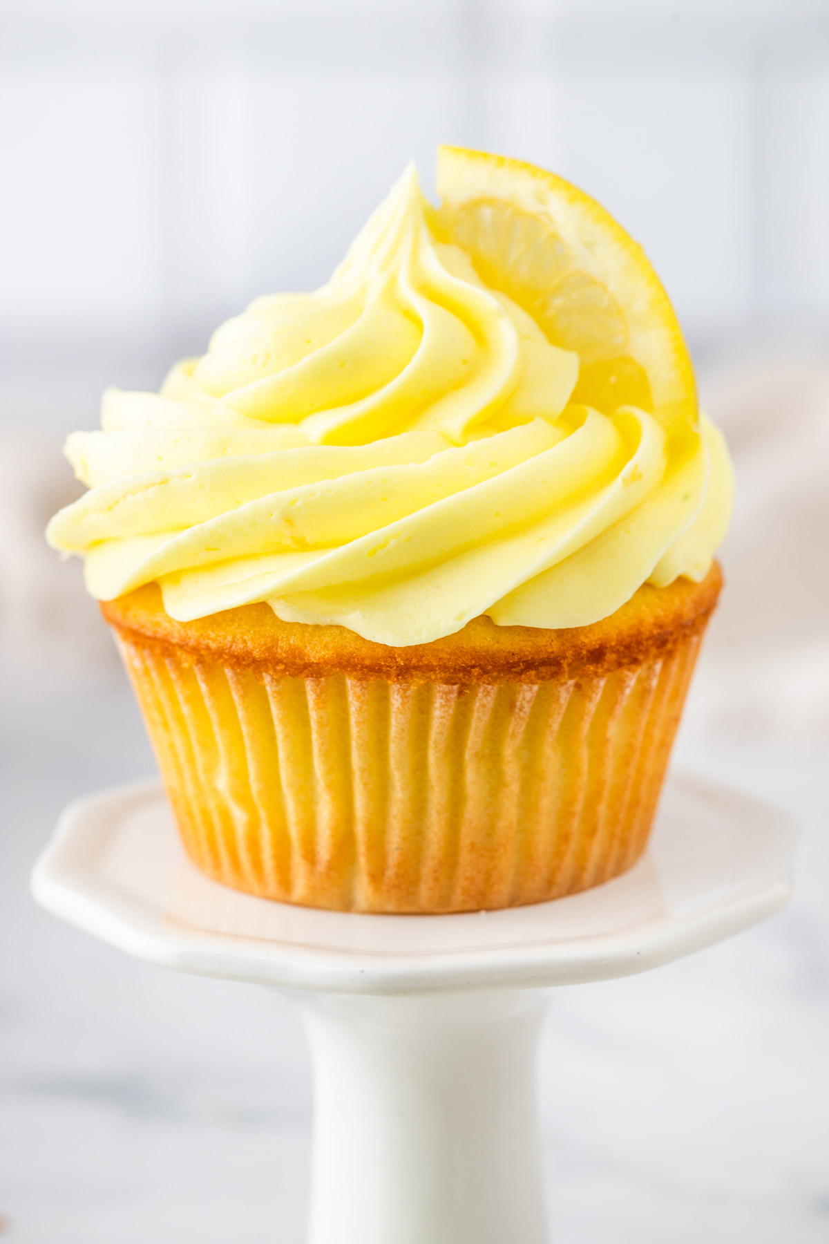 frosted lemon cupcake on a dessert stand.