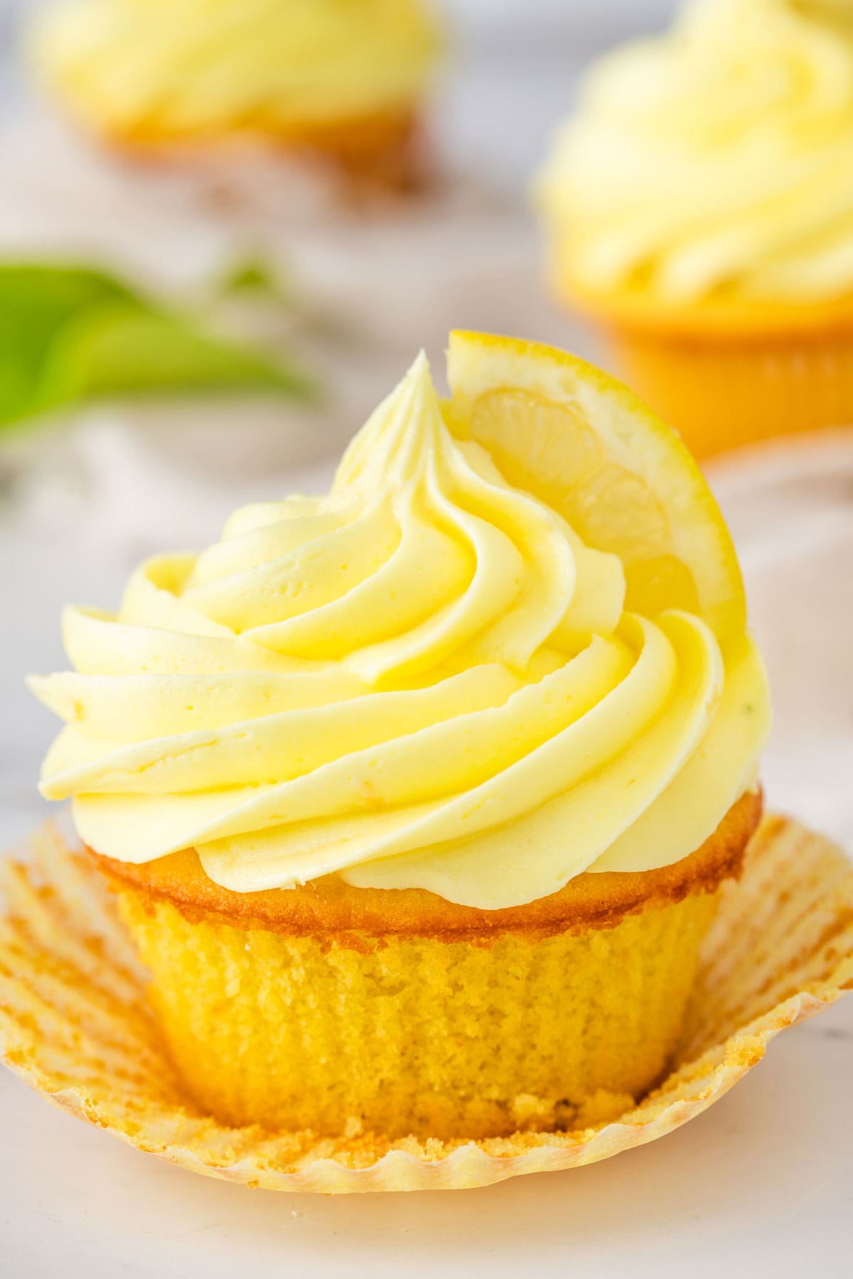 frosted lemon cupcake with the paper wrapper peeled down.