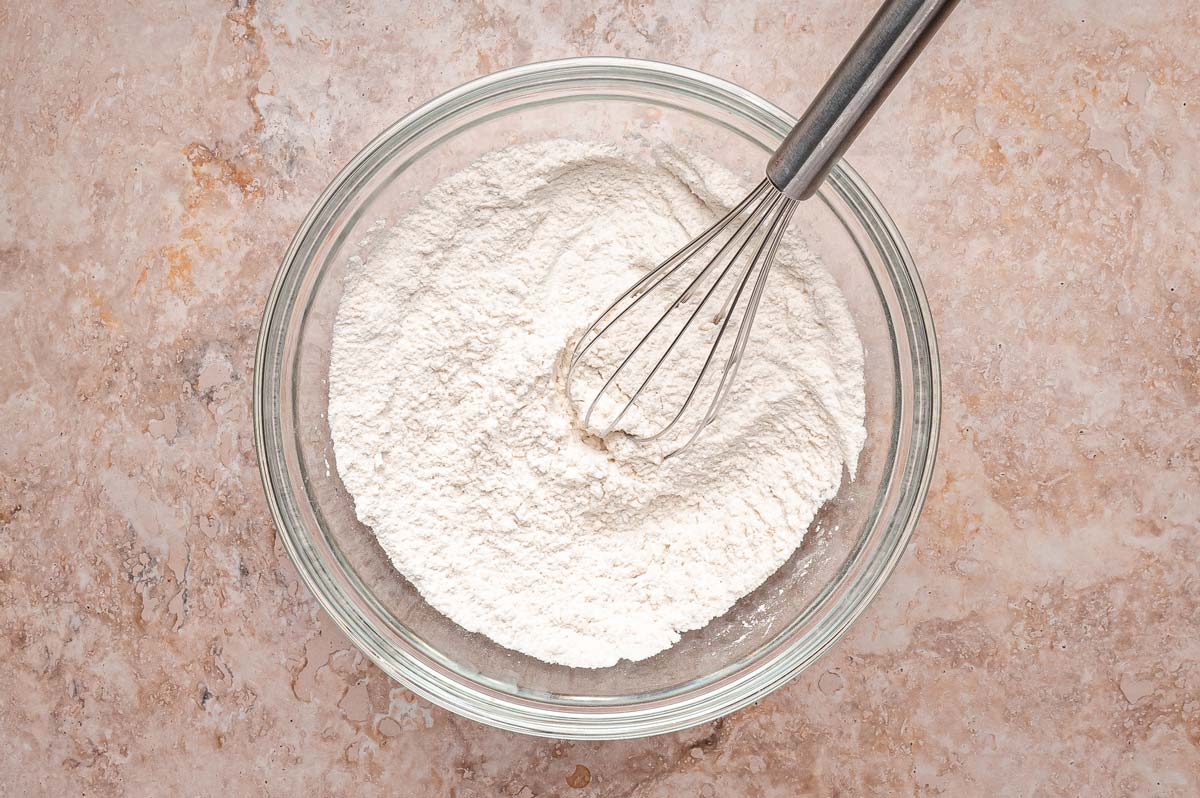 whisking dry ingredients in a glass mixing bowl.