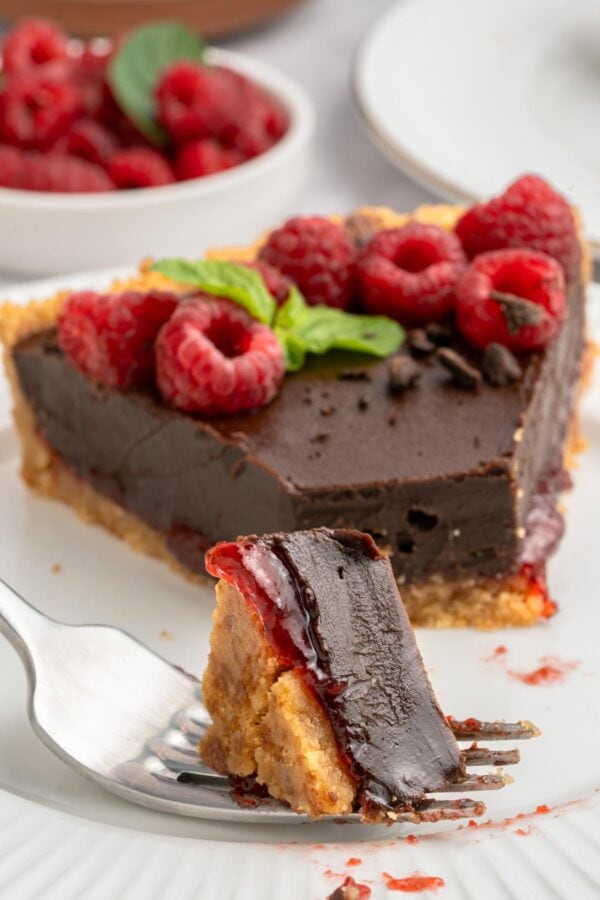 bite of raspberry chocolate tart on a fork highlighting the raspberry jam.