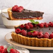 spatula lifting a slice of chocolate raspberry tart.