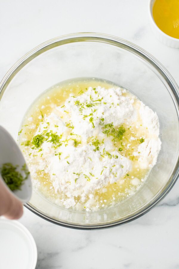 whisking lime cupcake batter in a glass mixing bowl.