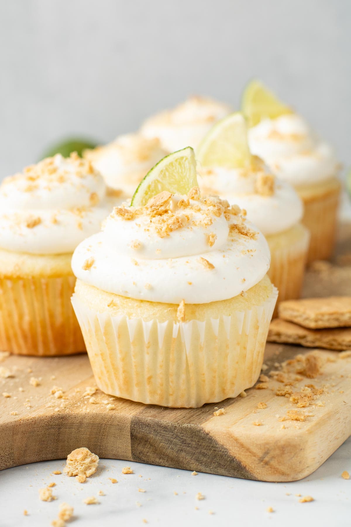 key lime pie cupcakes styled on a wooden cutting board.