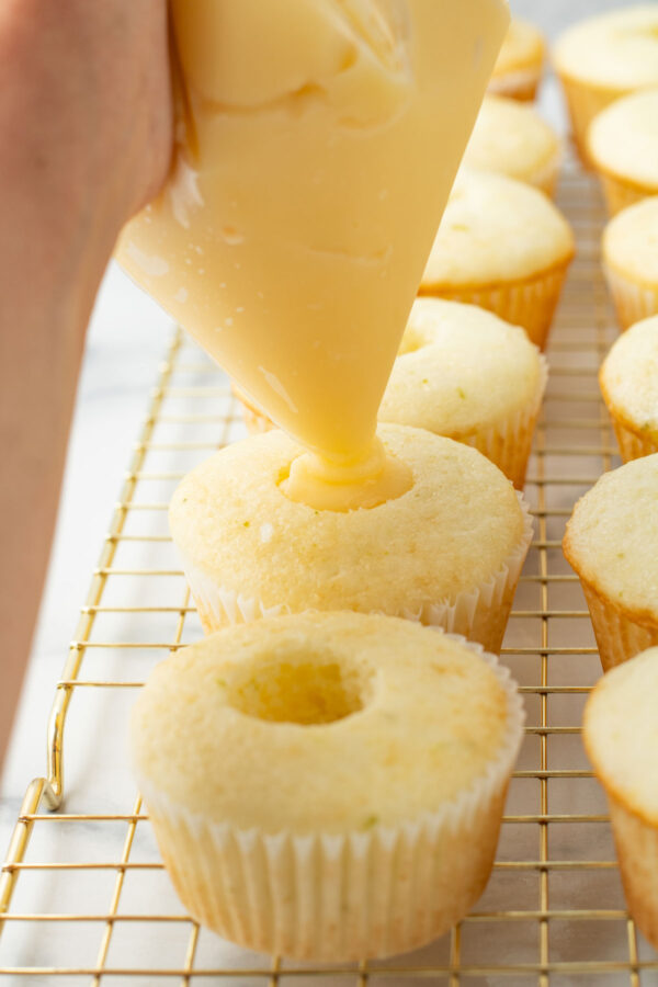 piping pudding filling inside a cored cupcake.