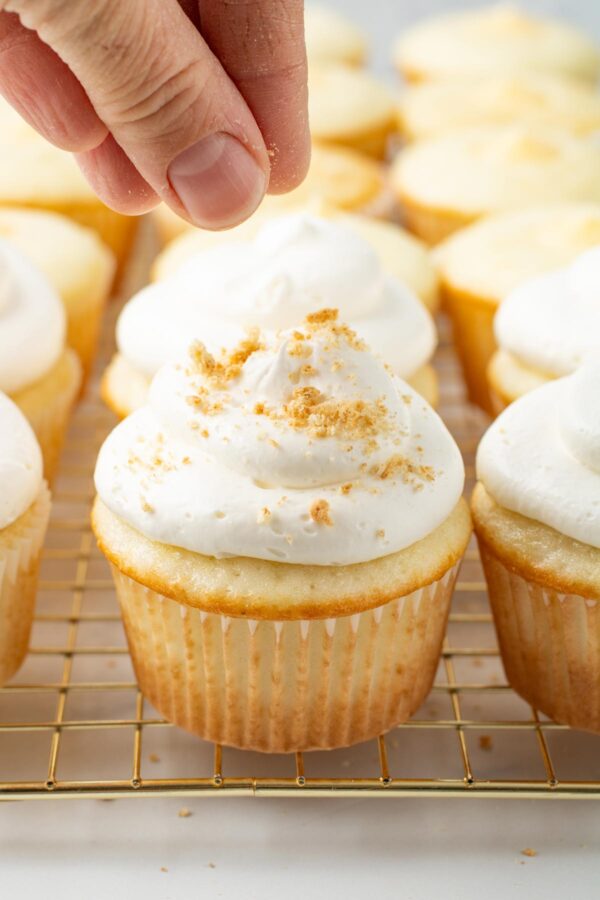 sprinkling graham cracker crumbs on a key lime pie cupcake.