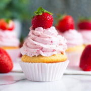 vanilla cupcakes topped with tall swirls of strawberry frosting.