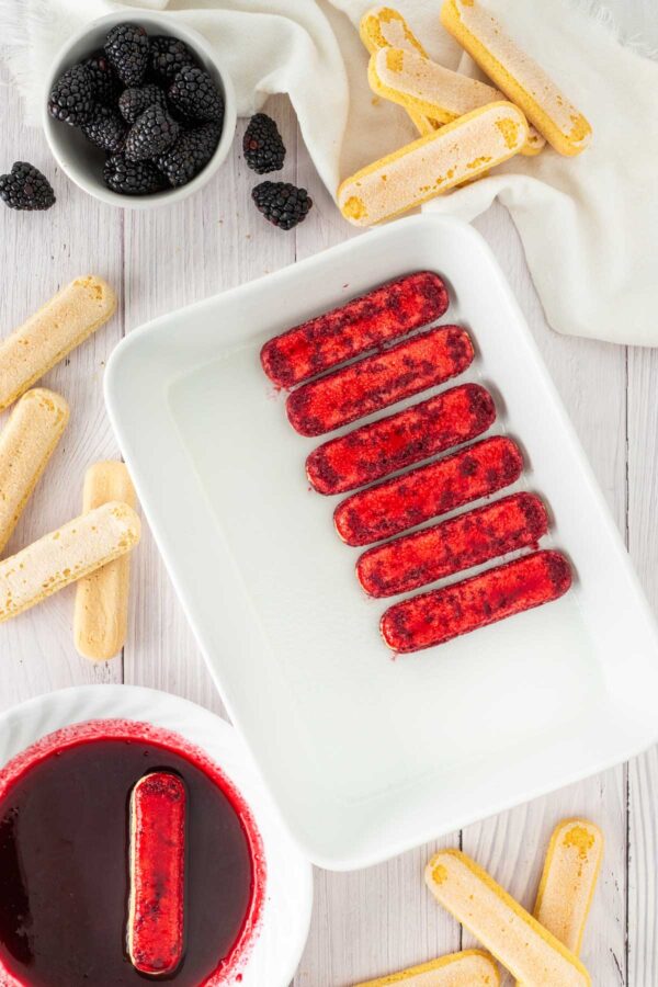 dipping ladyfinges in blackberry syrup.