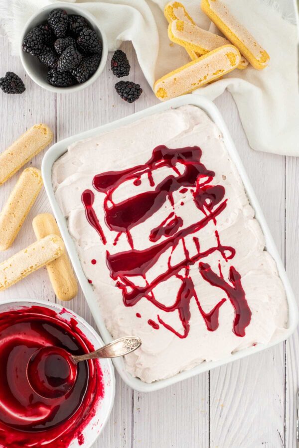 drizzling blackberry sauce over blackberry tiramisu.
