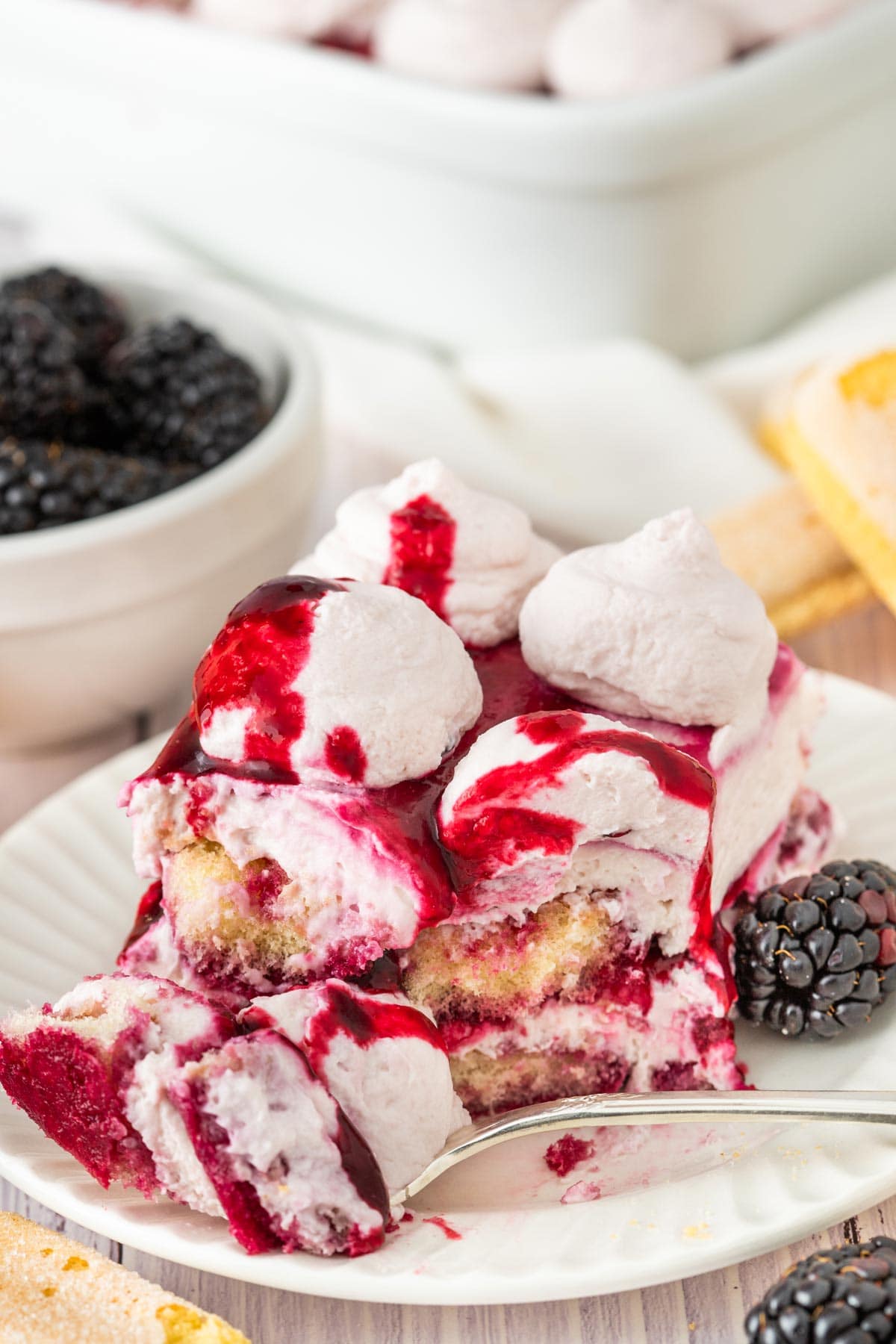 forkful of blackberry tiramisu drizzled with additional blackberry syrup.