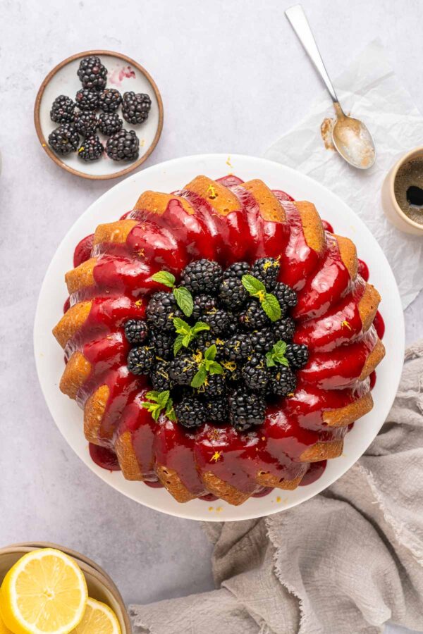 overhead view of a bundt cake with blackberry glaze filled with fresh blackberries.