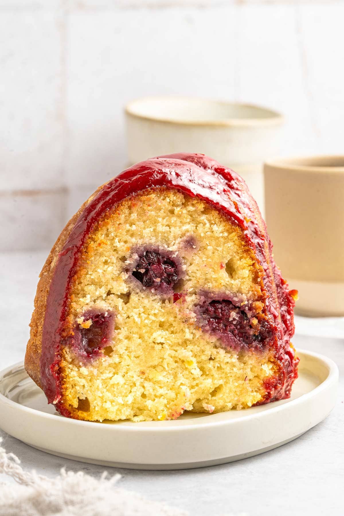 slice of lemon blackberry bundt cake showing the juicy blackberries inside the cake.