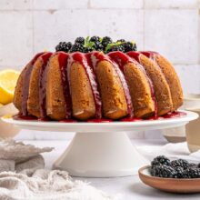 lemon blackberry bundt cake with lemon glaze on a cake stand.