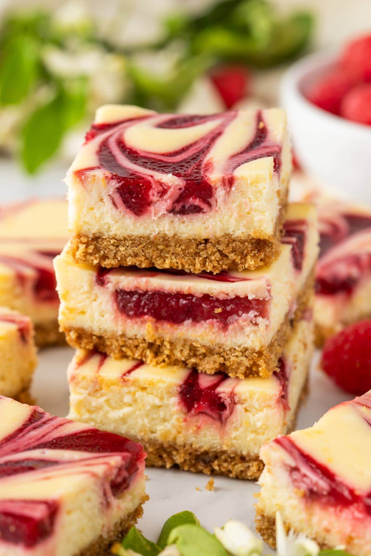 a stack of three lemon cheesecake bars with raspberry swirls.