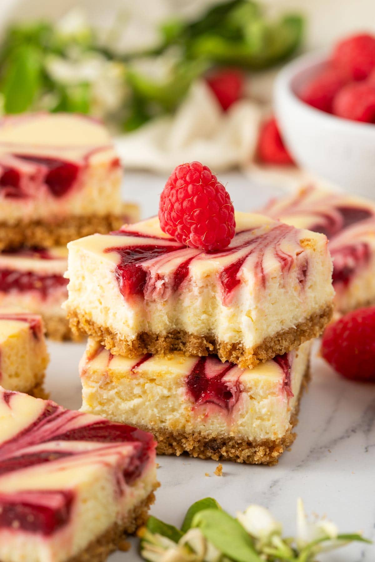 lemon raspberry cheesecake bars with a forkful removed from one.