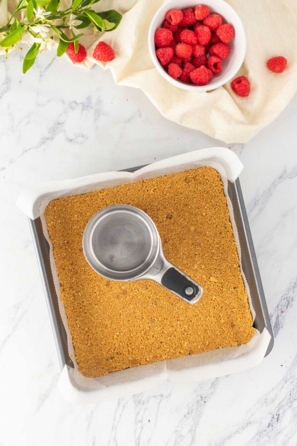 pressing graham cracker crumbs into a square baking pan.