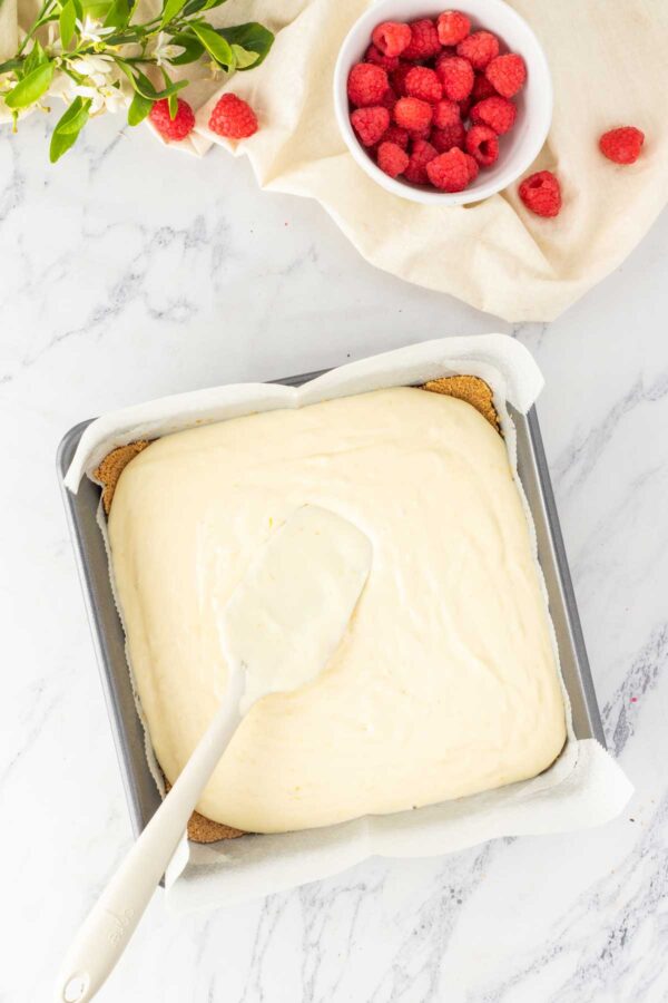 spreading cheesecake filling over the baked graham cracker crust.