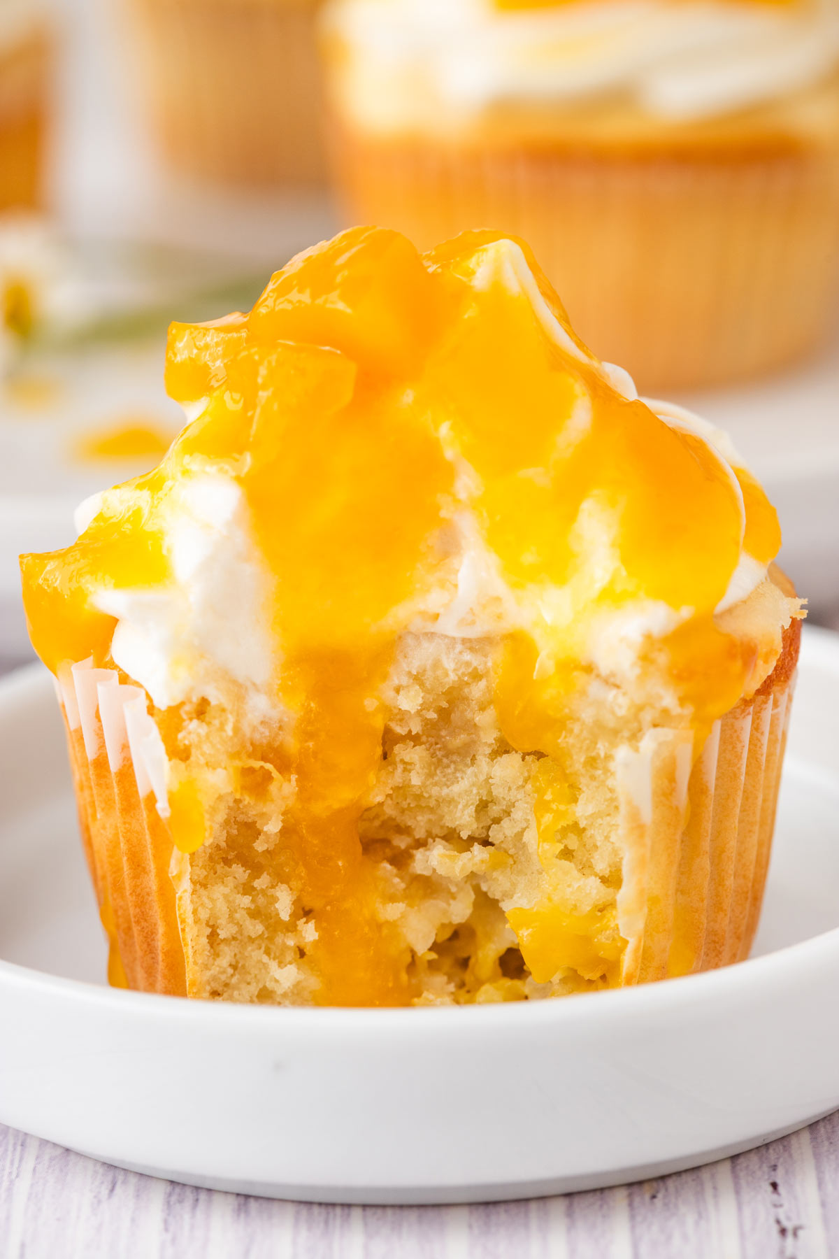 peach cupcake with a big bite taken out showing the fluffy interior.