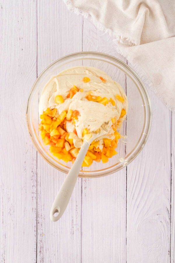 folding chopped fresh peaches into cupcake batter.