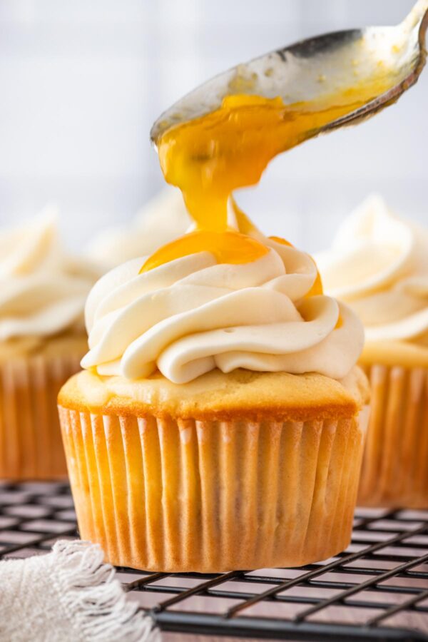 spooining peach glaze on top of peach cupcakes.