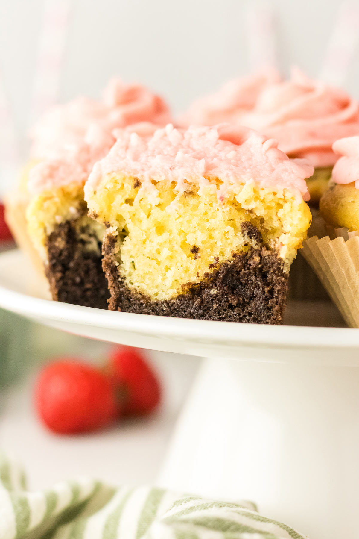 side view of a neapolitan cupcake highlighting the chocolate, vanilla, and strawberry layers.