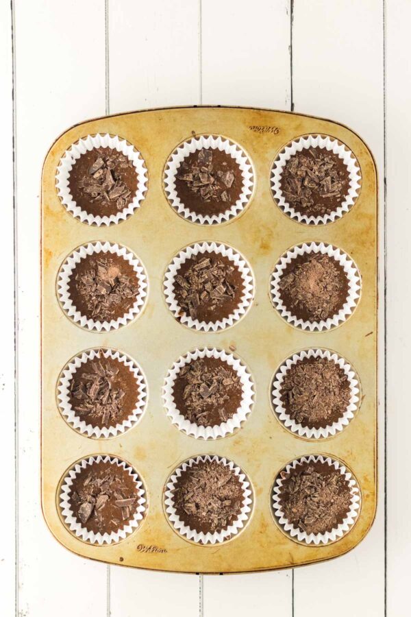 cupcake liners filled with chocolate cake batter and sprinkled chocolate.