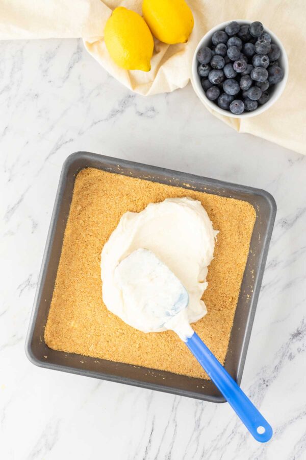 spreading lemon cream over a graham cracker crust.