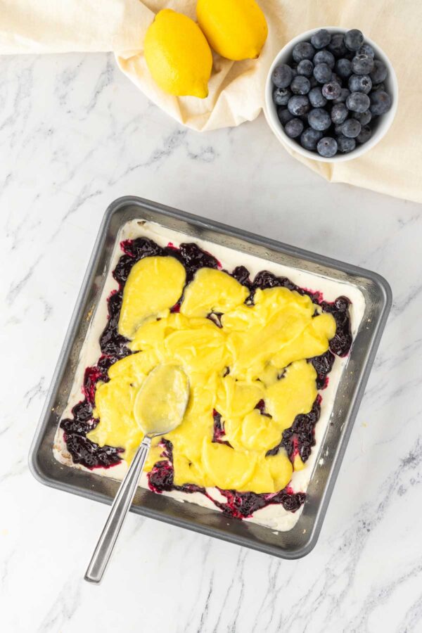 spreading lemon curd onto a no bake cheesecake.
