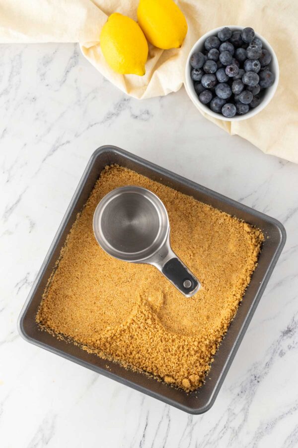 pressing a graham cracker crust into a baking dish.
