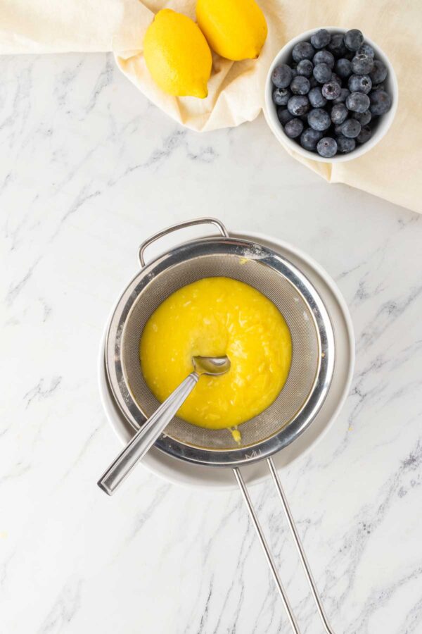 straining lemon curd through a mesh sieve.
