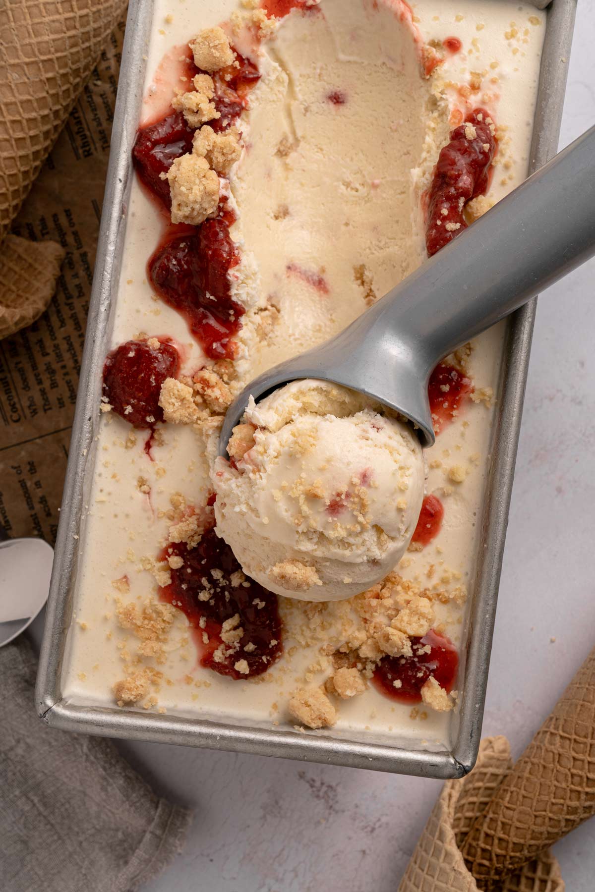 scooping homemade strawberry shortcake ice cream with a metal ice cream scoop.