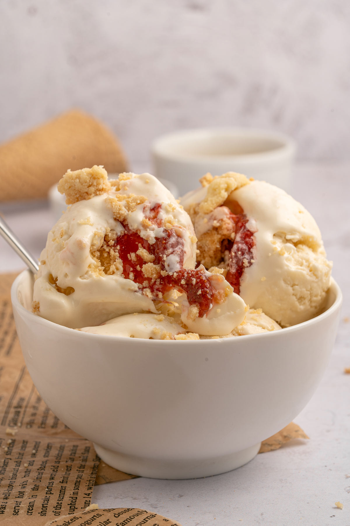 big bowl of vanilla ice cream with strawberry swirls and shortbread crumble.