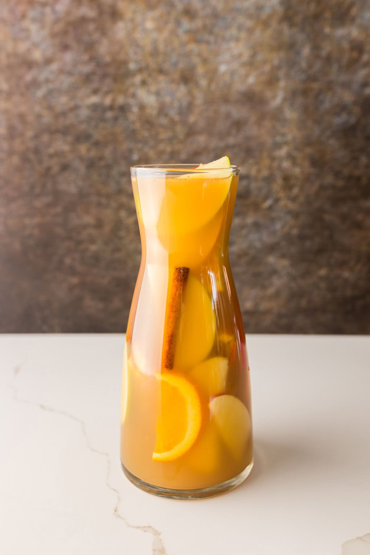 pitcher of apple cider sangria filled with slices apples and oranges.