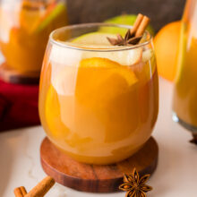 glass filled with cut fruit and apple cider sangria.
