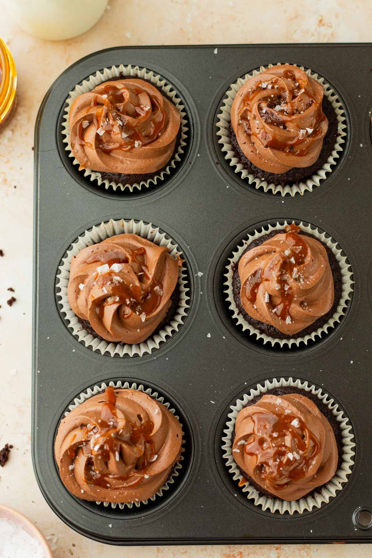 frosted chocolate cupcakes in a cupcake tin.