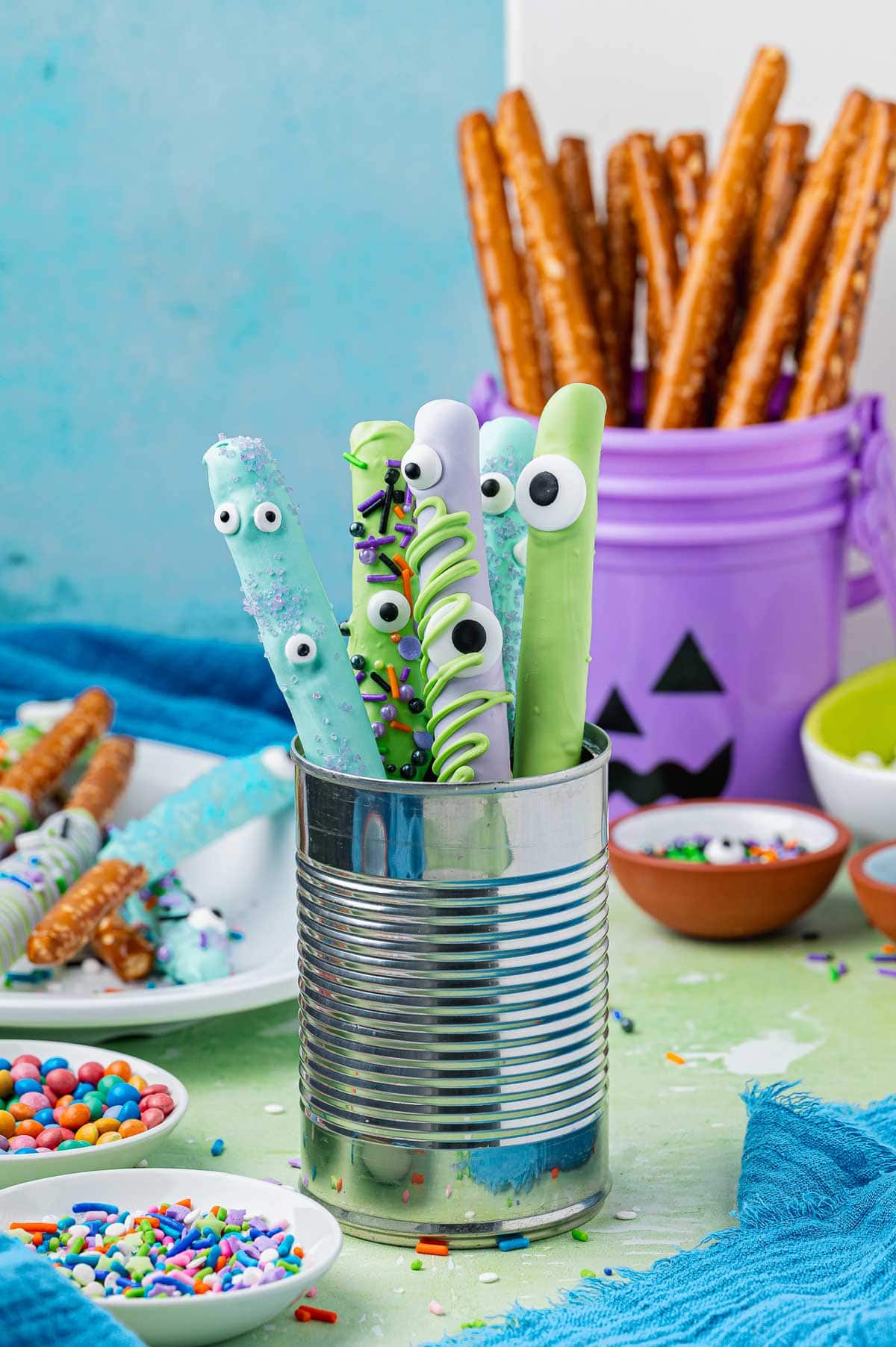 pretzel rods decorated to look like monsters upright in a tin can.