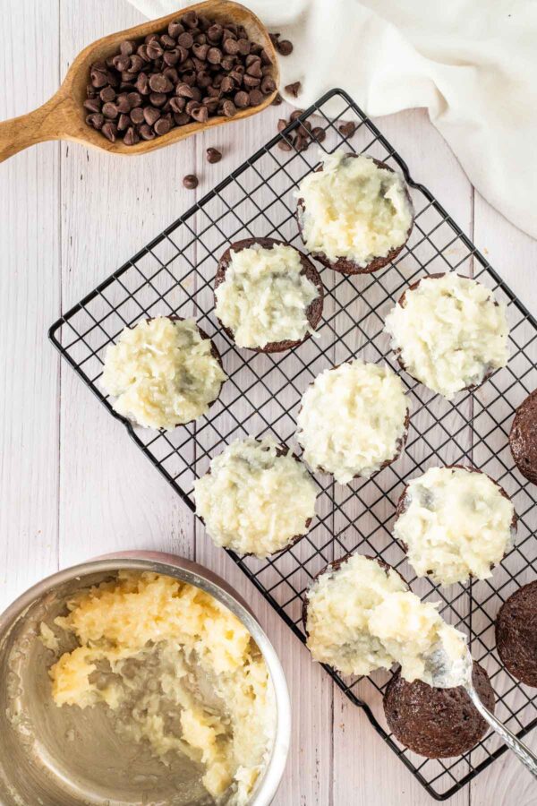 covering chocolate cupcakes with a layer of coconut.